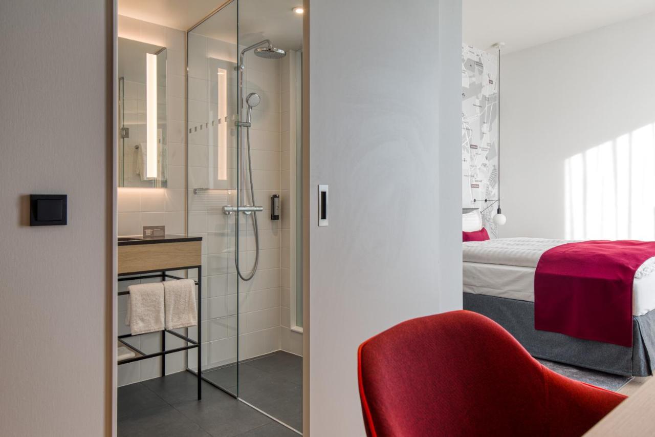 Intercityhotel Berlin Airport Ber Terminal 1 & 2 쇼네펠드 외부 사진 The photo shows a modern hotel room or bathroom space. On the left, there is a glass-enclosed shower area with a sleek design, featuring a showerhead and minimalist fixtures. Adjacent to the shower, there's a sink area with a stylish countertop and a